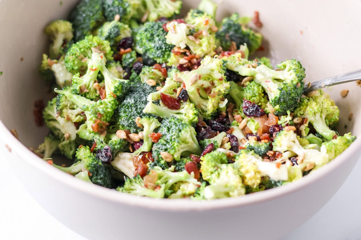 Mixing broccoli and dressing in a bowl.