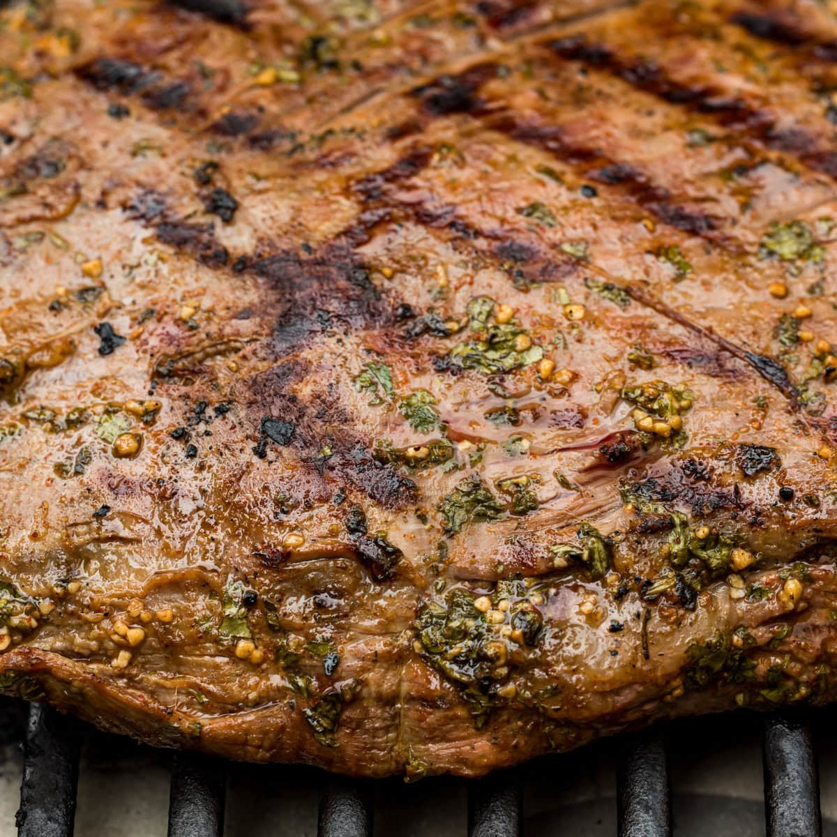 Close up of flank steak cooking on a grill.