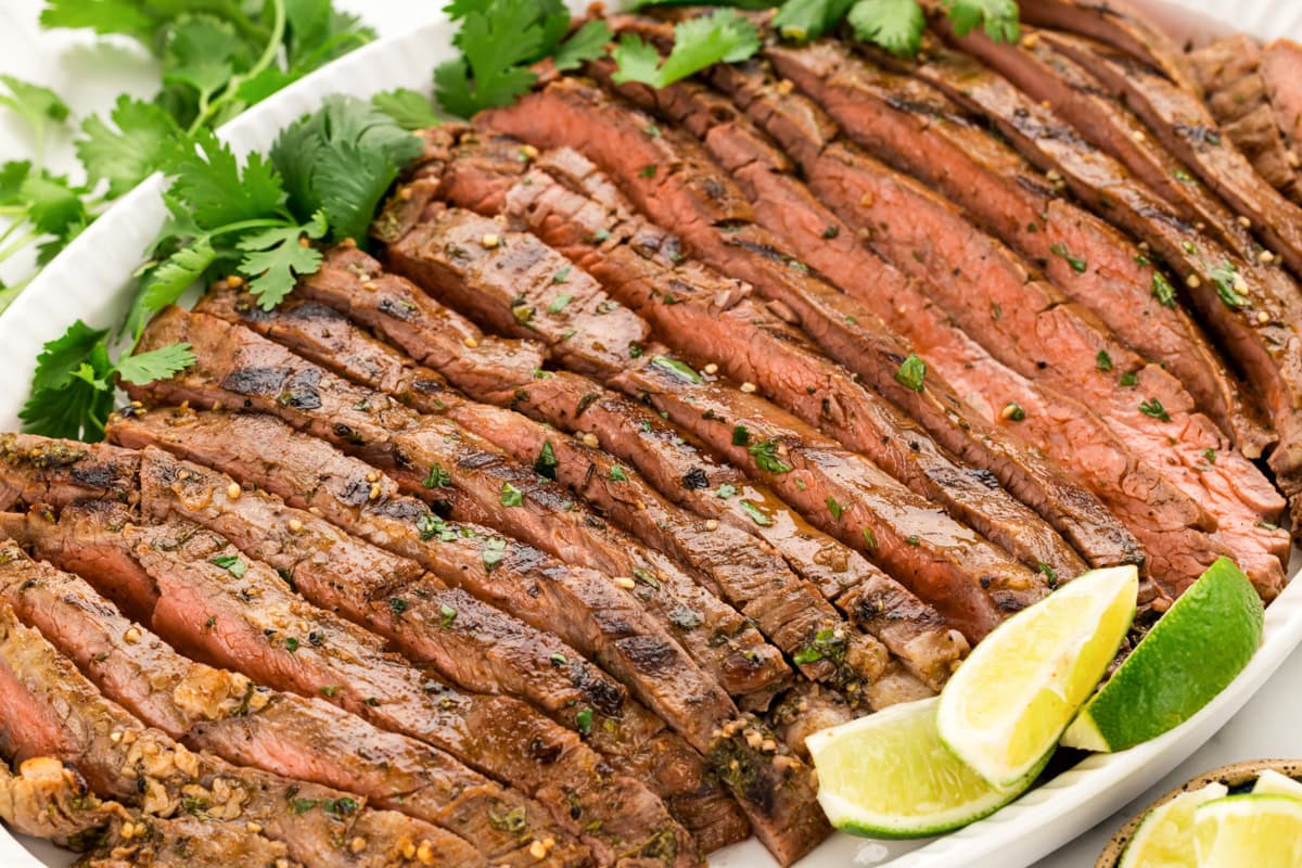 Sliced carne asada recipe on a white platter.
