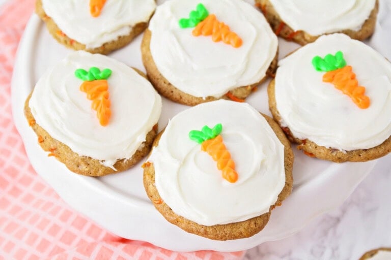Carrot cake cookies with carrot piped on top on cake stand.