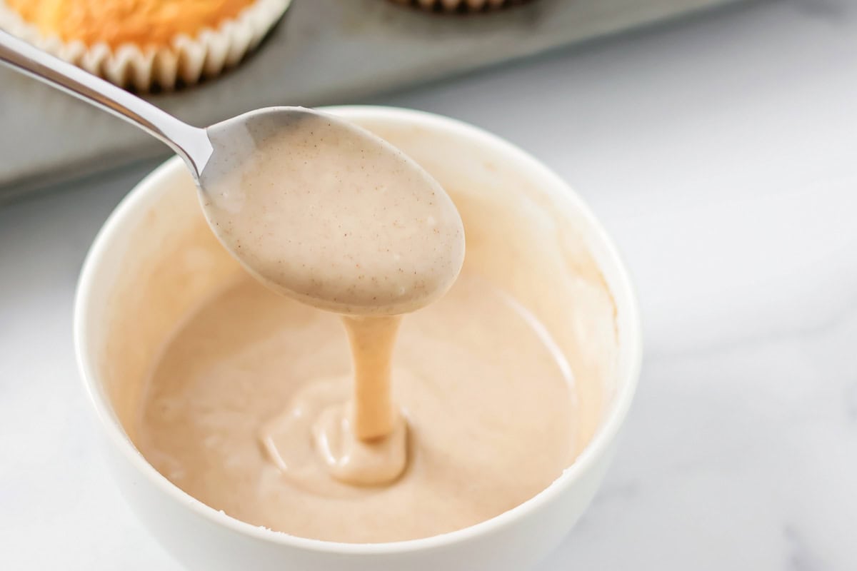 Carrot cake muffins glaze in white bowl.