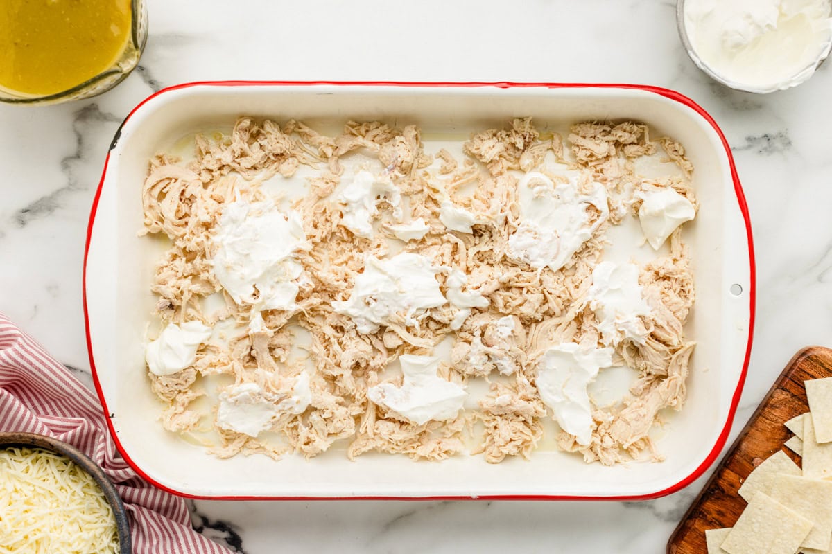 Topping the shredded cheese with sour cream.