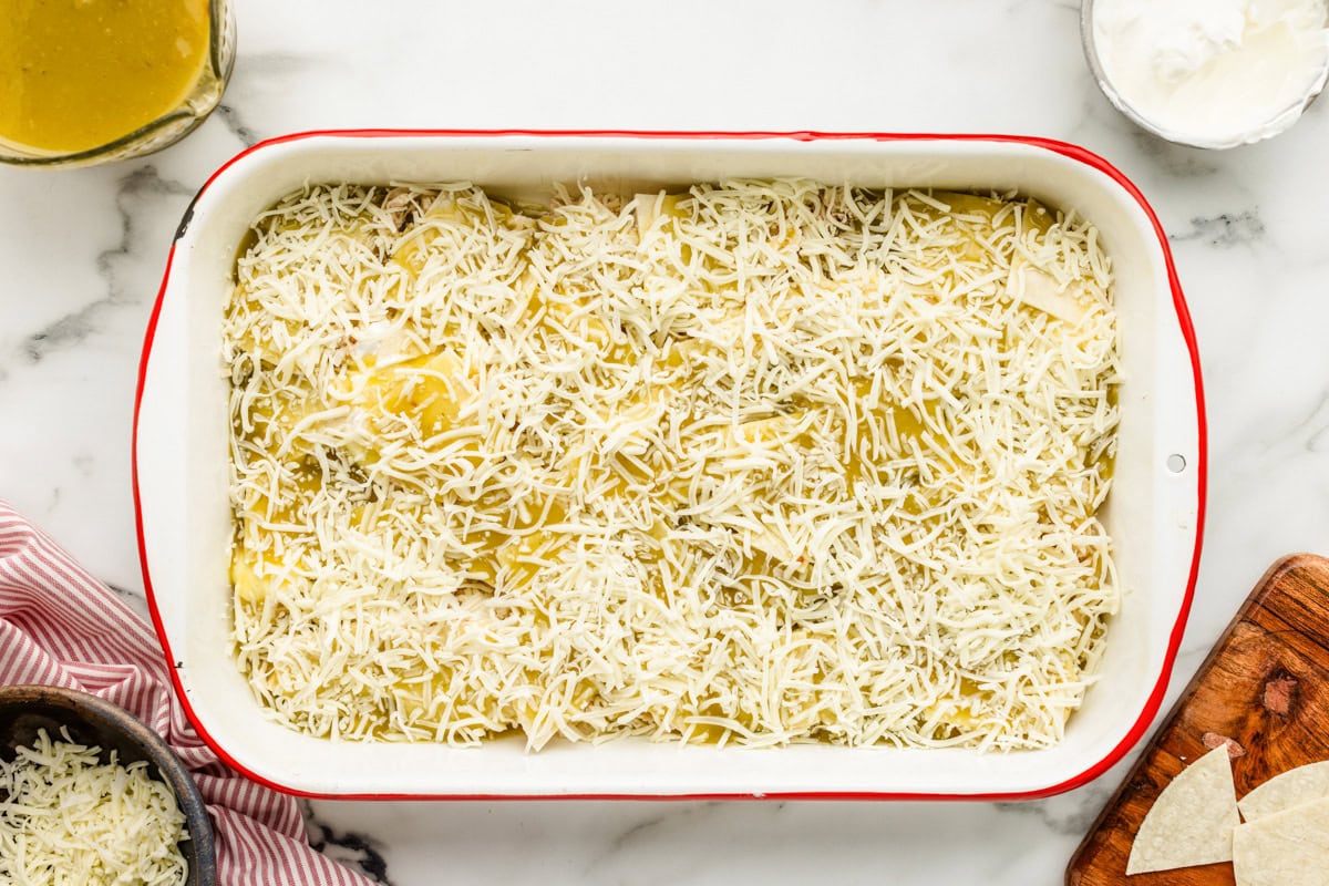 Adding a layer of cheese to the casserole.