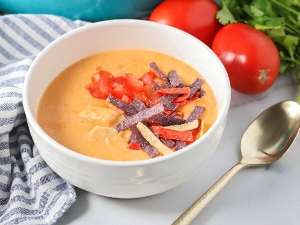 Chili's chicken enchilada soup recipe in bowl with tortilla strips on top.