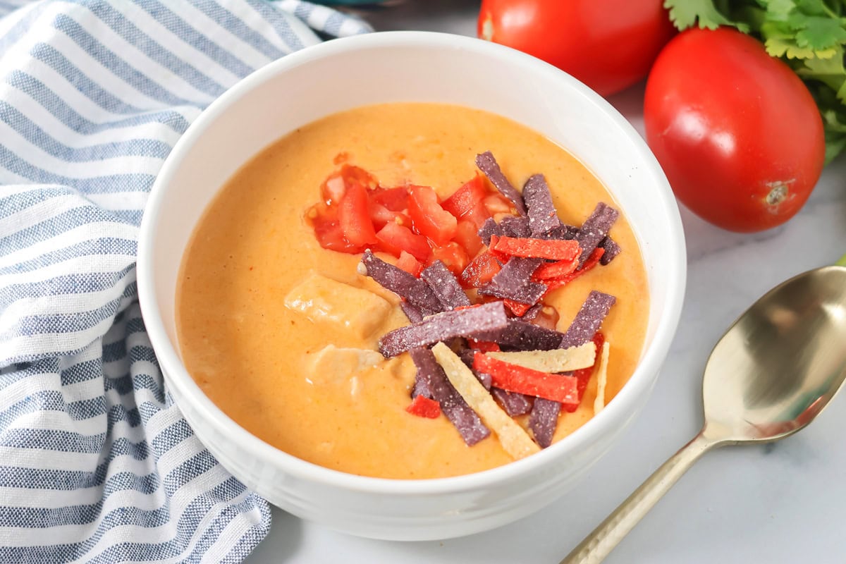 Thick and cheesy Chili's chicken enchilada soup tastes just the original! With mostly shelf-stable ingredients it's our favorite go-to soup. Chili's chicken enchilada soup served in a white bowl.