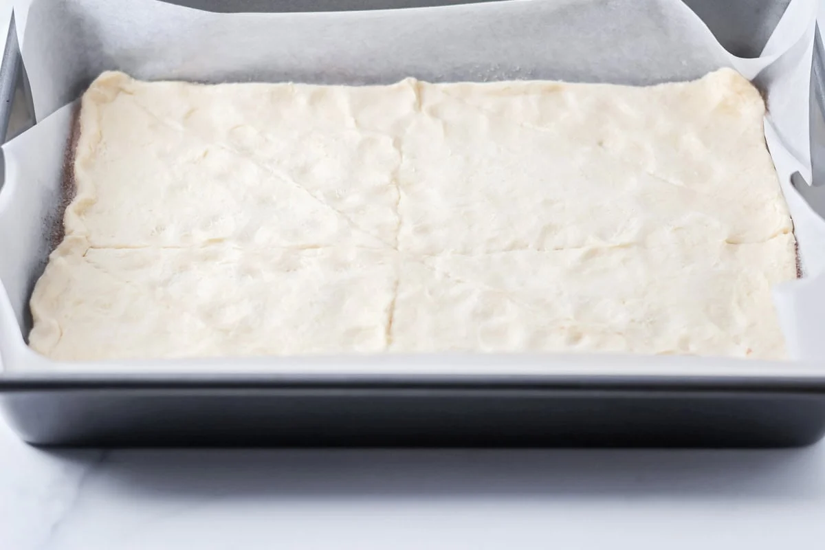 Crescent dough pressed in a lined baking pan.