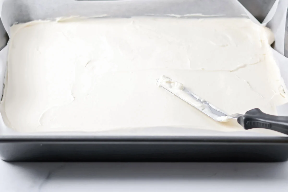 Spreading cream cheese mixture over the crescent dough.
