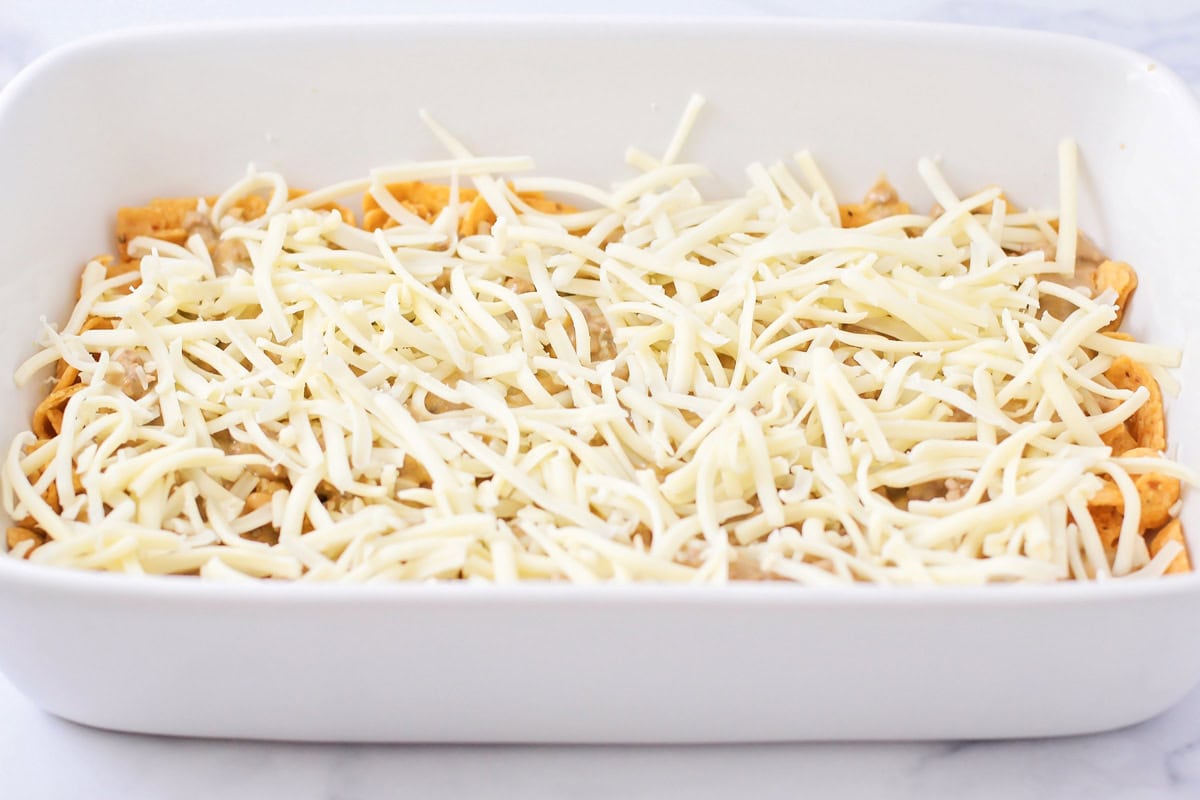 Adding a layer of shredded cheese to the pan.