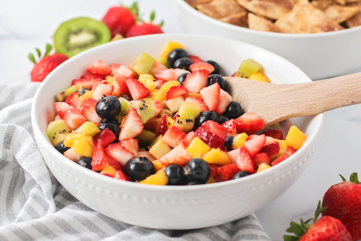 Fresh fruit salsa is a perfect pairing for our sweet homemade cinnamon chips. Ready in under 20 minutes, you can make it for any occasion! A bowl of fresh fruit salsa in a white bowl.