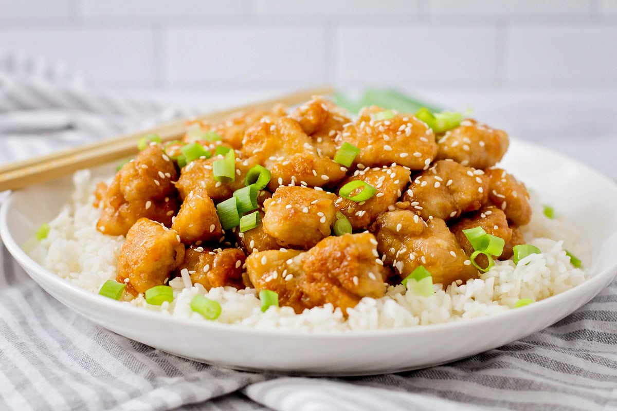 General Tso's chicken served over a bed of rice and topped with green onions and sesame seeds.