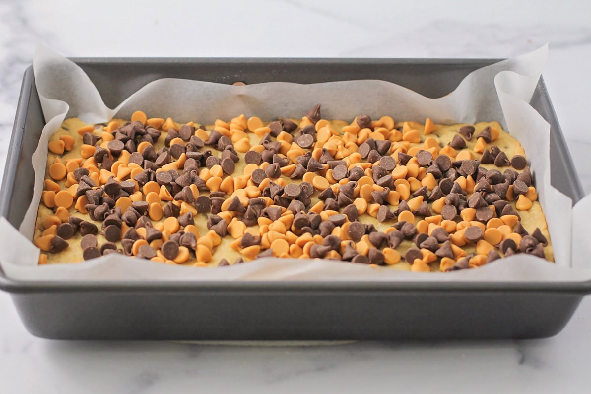 Layering chocolate and butterscotch chips on top of the baked cookie crust.