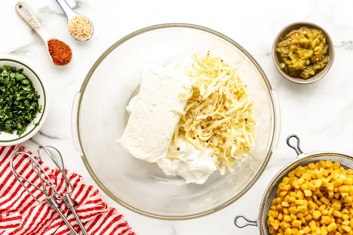 Combining cream cheese and shredded cheese in a glass bowl.