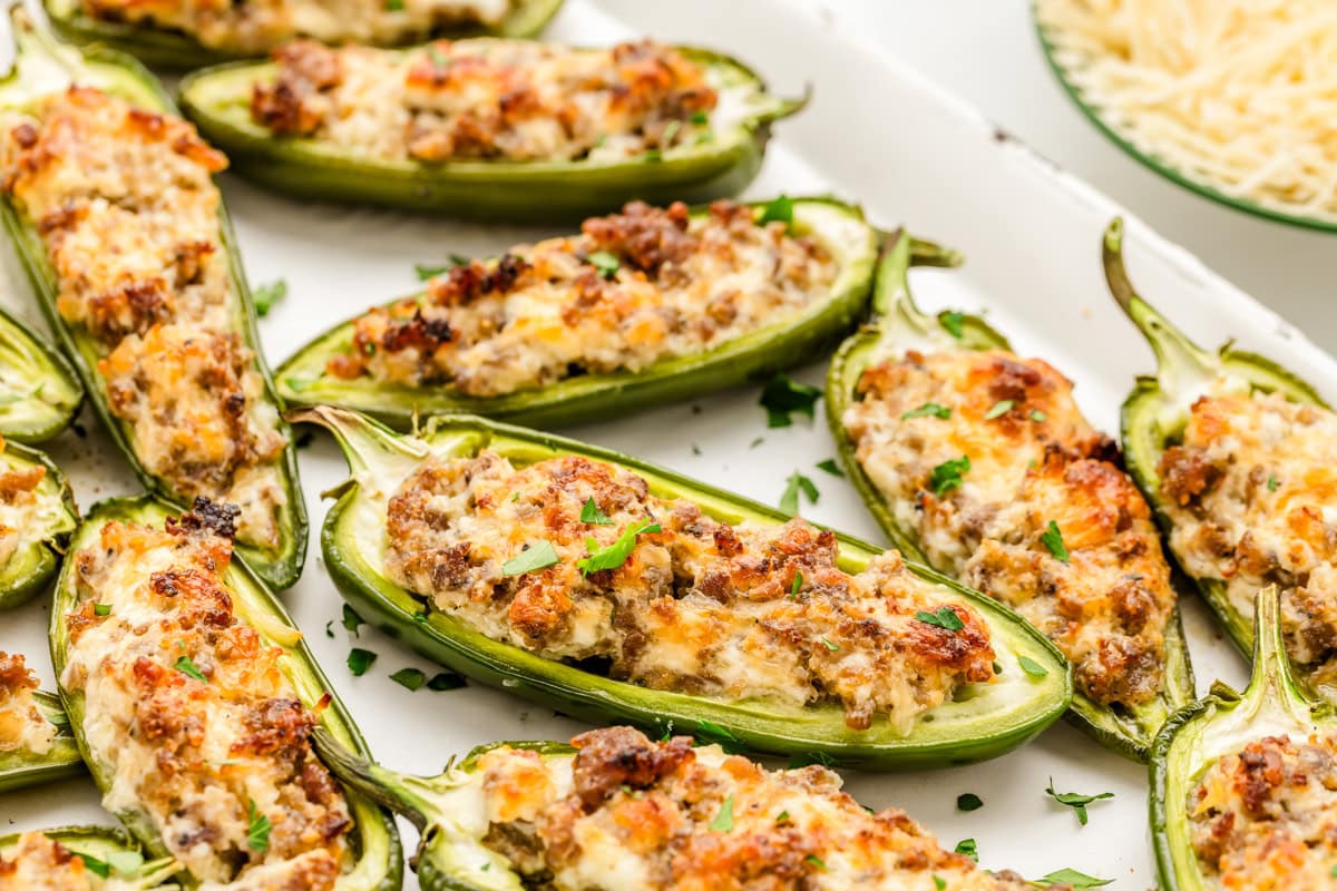 Close up of sausage stuffed jalapenos served on a white tray.