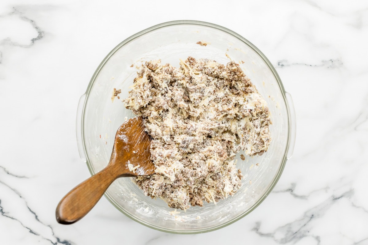 Stirring the cream cheese sausage mixture in a glass bowl.