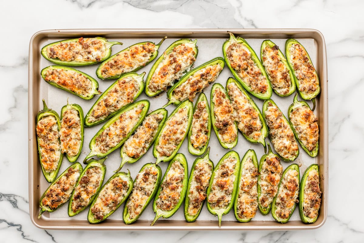 Cooked stuffed jalapenos on a baking sheet.