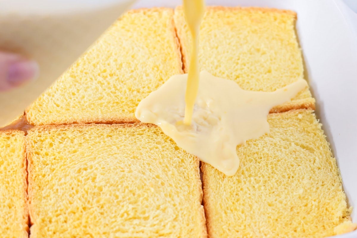 Pouring egg mixture on top of bread.