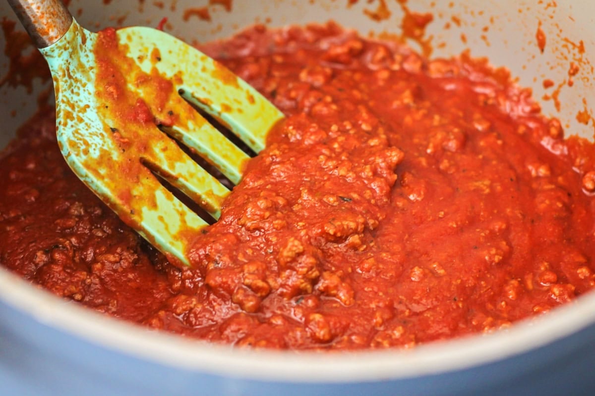 Tomato and meat sauce cooking in a pan on the stove.