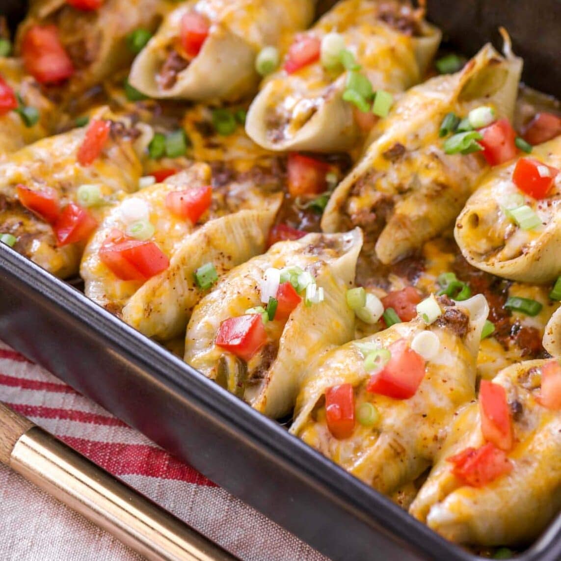 Close up image of taco stuffed shells in baking dish.