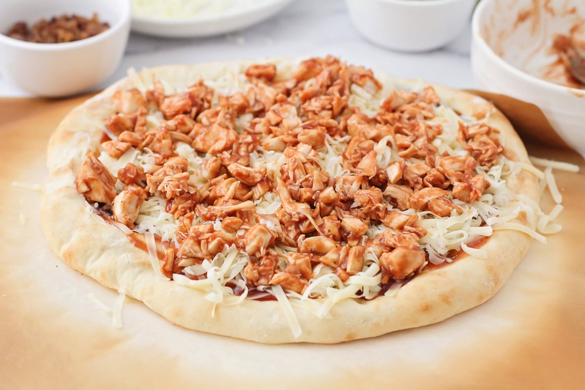 Adding bbq chicken and cheese to the pizza crust.