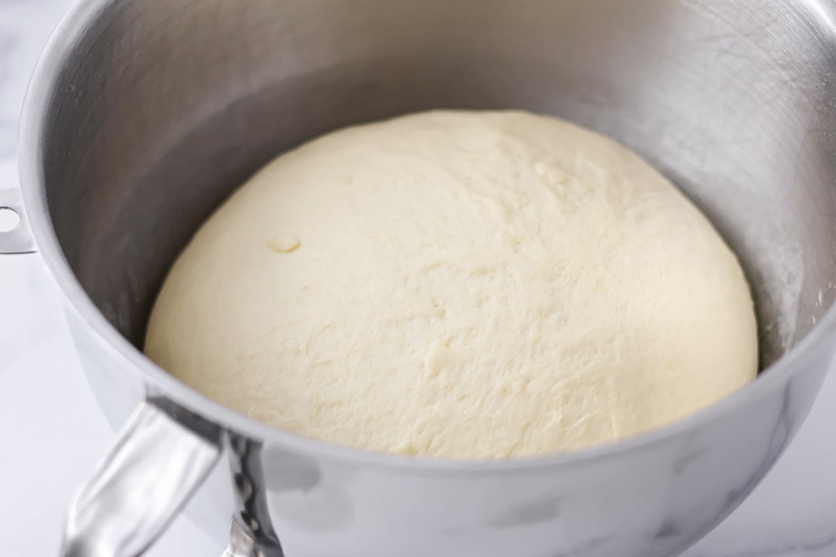 Dough ball rising in a metal bowl.