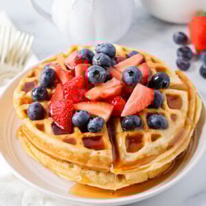 Buttermilk waffles stacked on top of each other with berries on top.