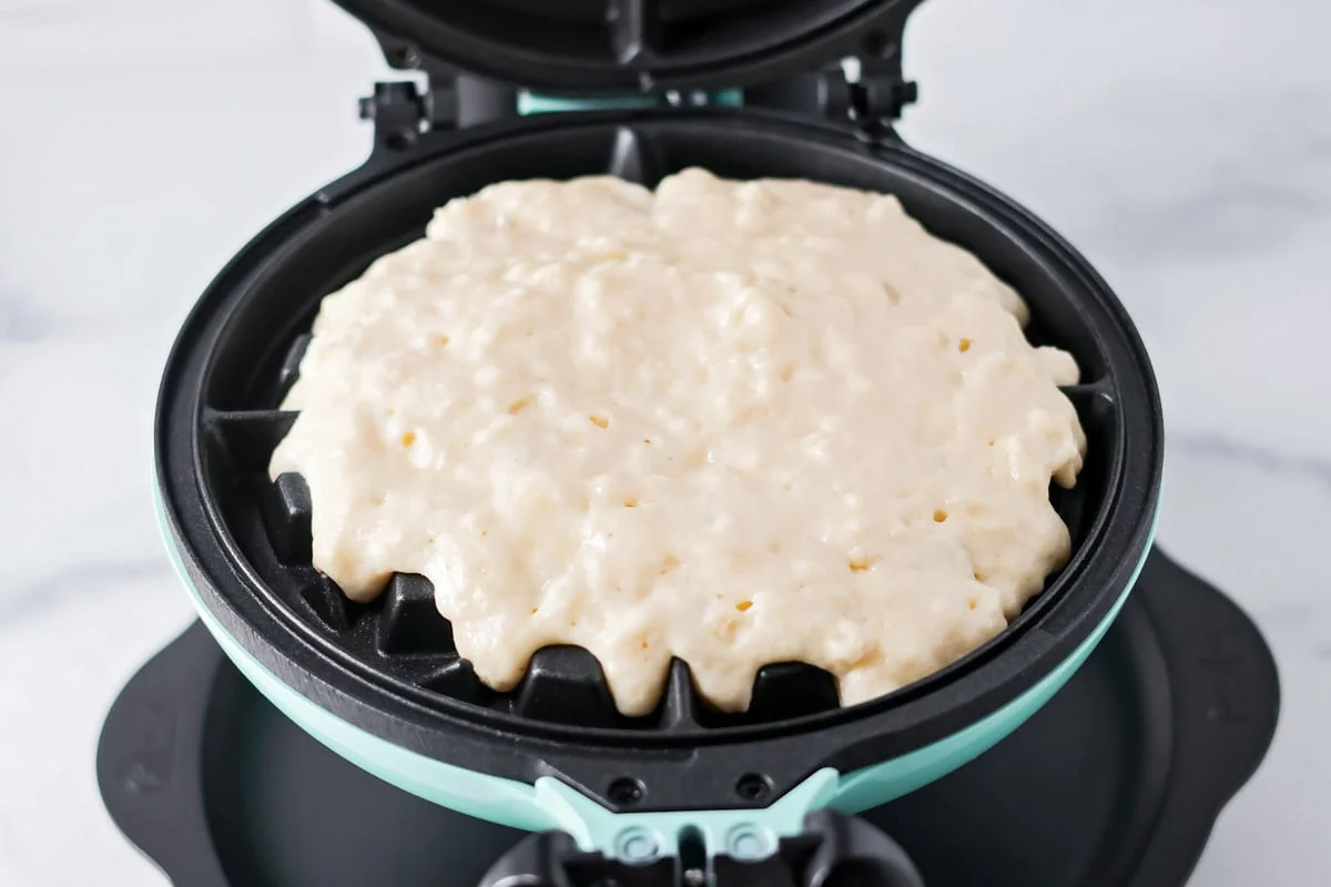 Our no-fail recipe for delicious, fluffy buttermilk waffles is morning perfection every time - guaranteed! Adding buttermilk waffle batter to a waffle maker.