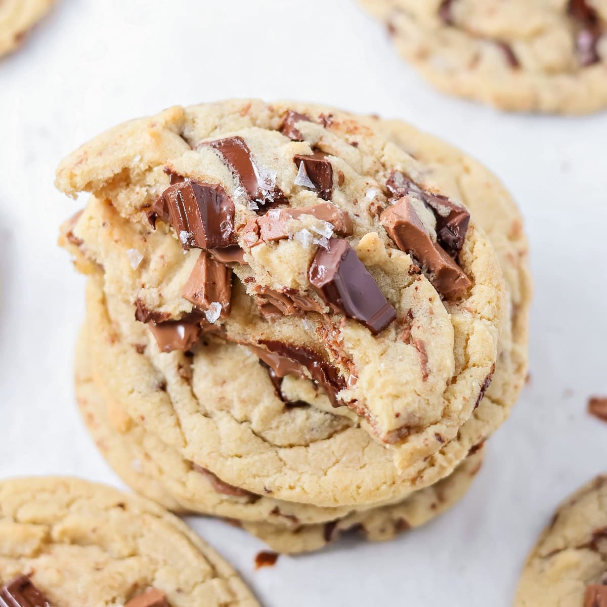 A stack of chocolate chunk cookies with a bite missing from the top cookie.