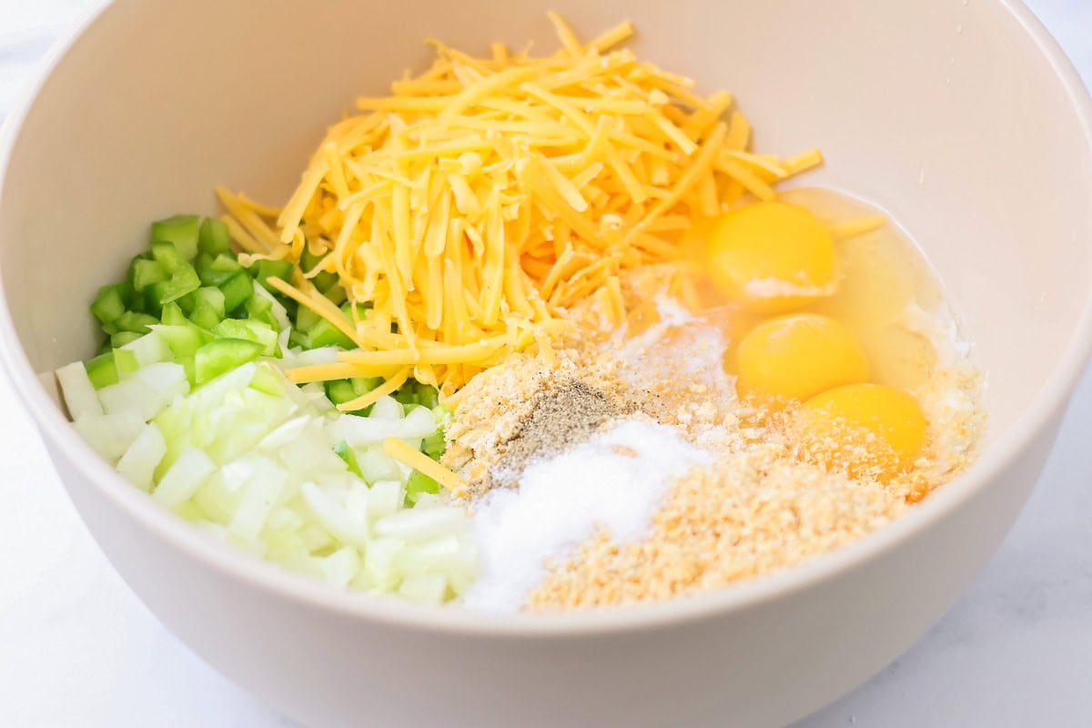 Eggs, cheese, veggies, and seasonings in a bowl.