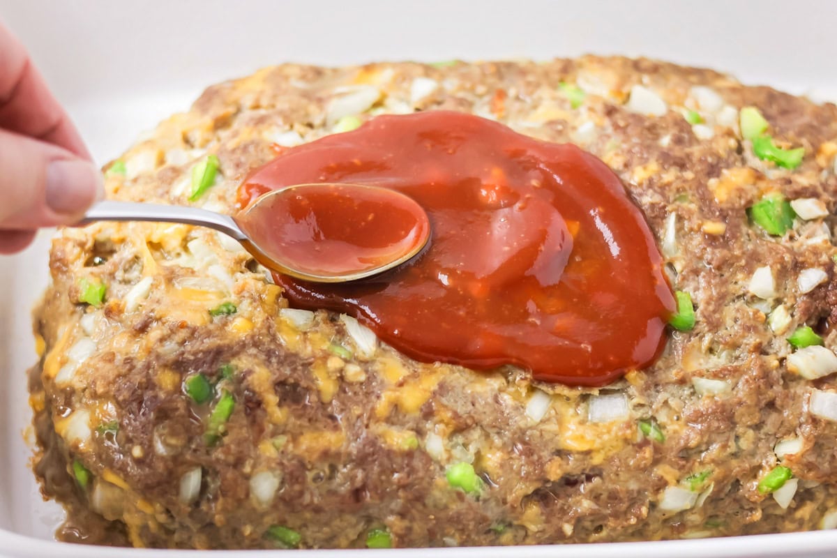 Spreading ketchup glaze onto the meatloaf.