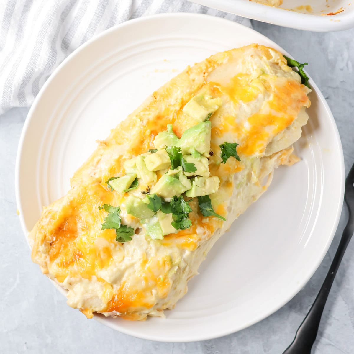 Two creamy chicken enchiladas on a white plate.