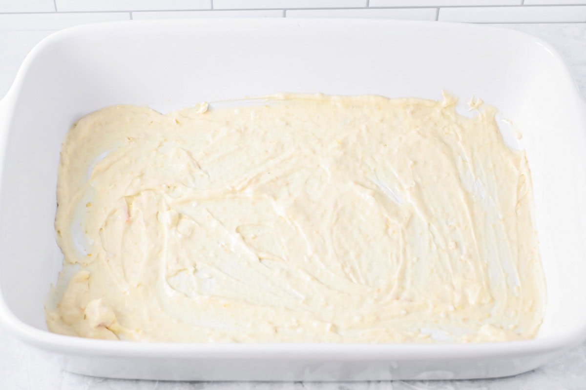 Spreading the chicken mixture in the bottom of a baking dish.
