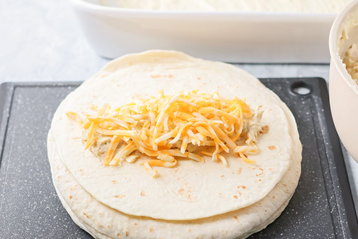 Filling tortillas with chicken and cheese.