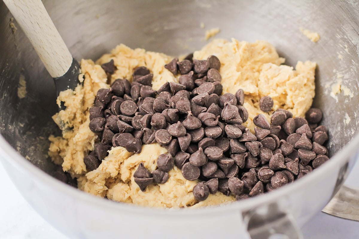 Adding chocolate chips to the cookie batter.