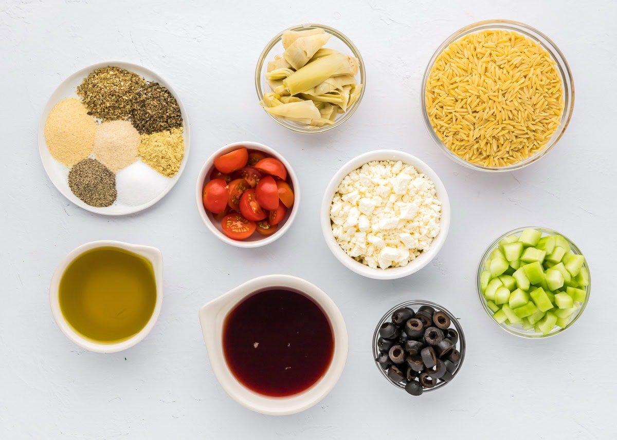 Ingredients for greek orzo pasta salad on a kitchen counter.