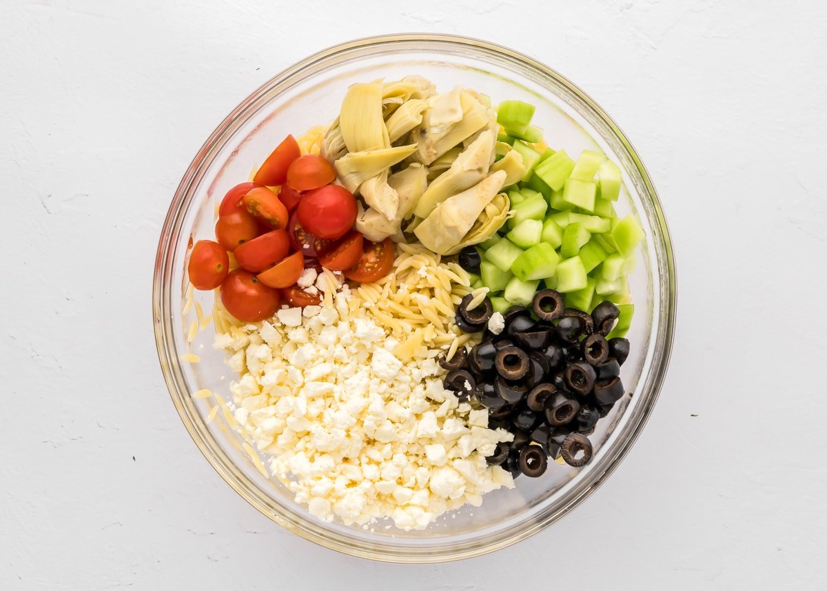 Veggies and cheese chopped in a glass bowl.