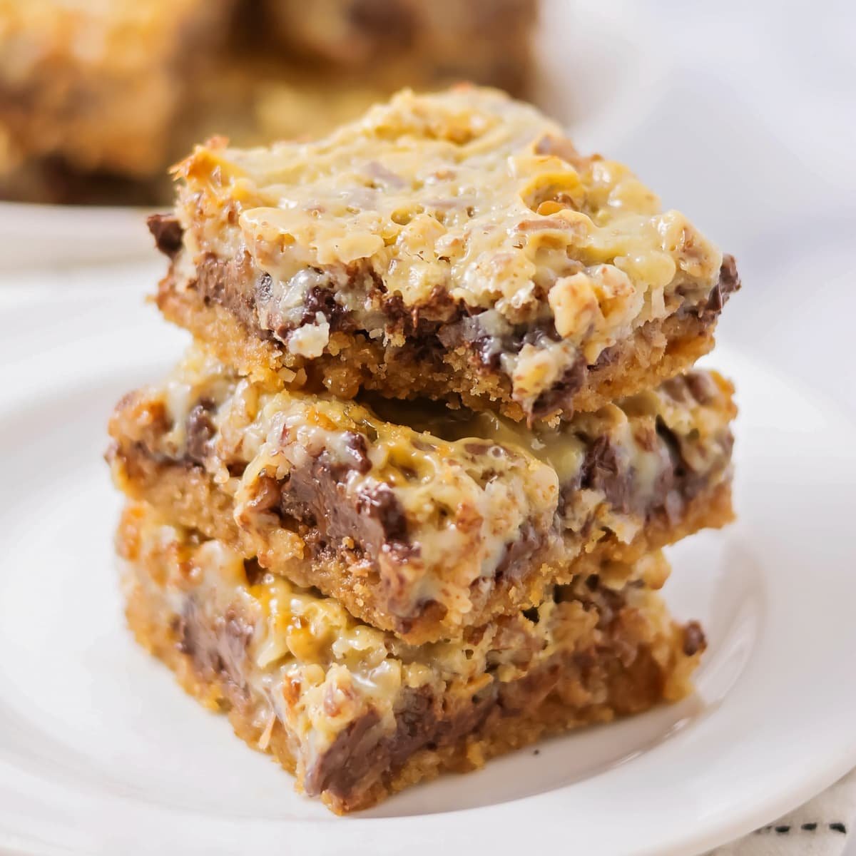 Hello dolly bars stacked  on a white plate.