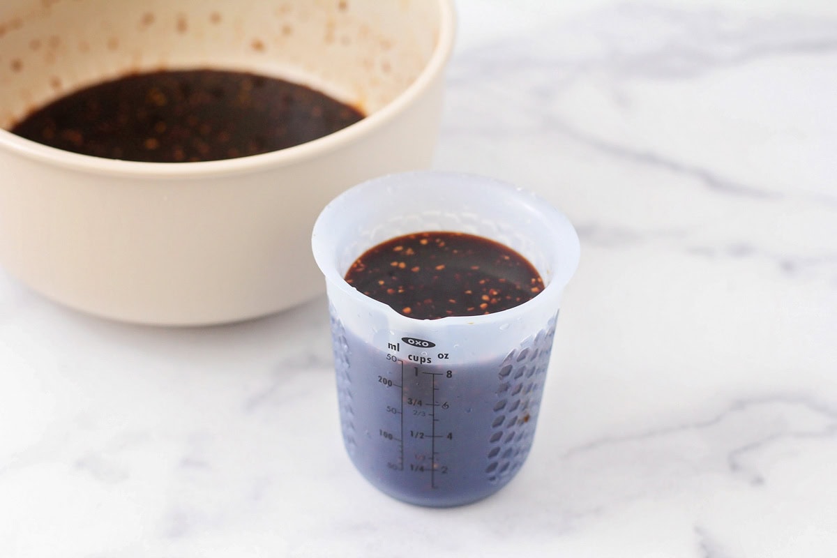 Grilled Huli Huli chicken is juicy, smoky, and glazed with a sweet and tangy Hawaiian-style marinade! Serve it alone or on rice or noodles. Huli Huli marinade in a measuring cup.