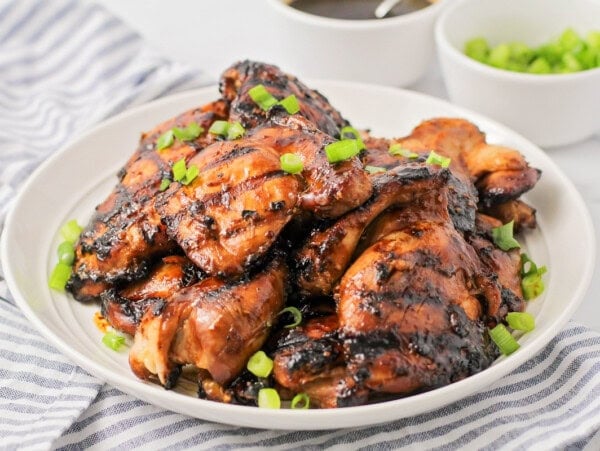 Grilled Huli Huli chicken stacked on top of each other on white plate.