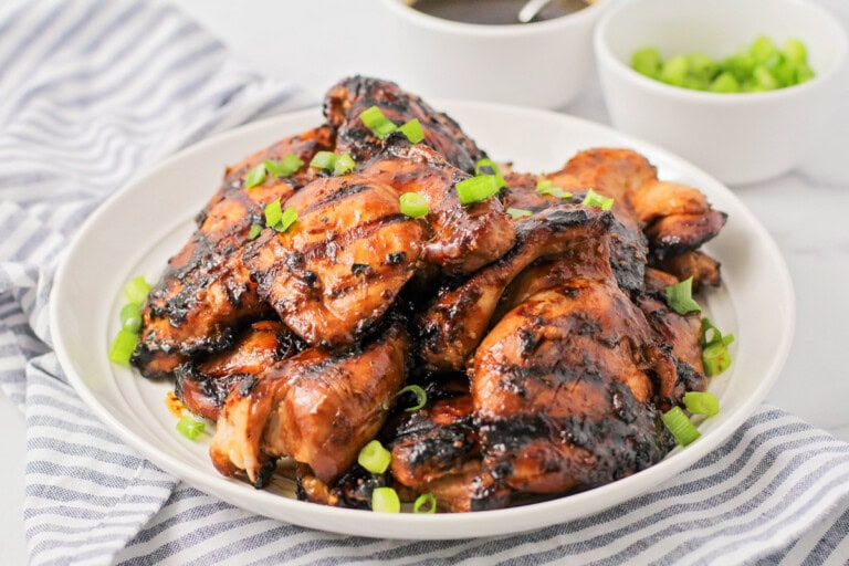 Grilled Huli Huli chicken stacked on top of each other on white plate.