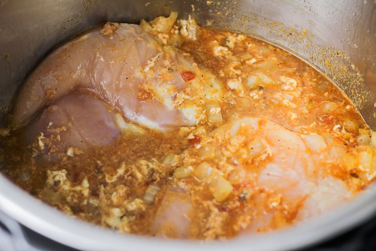 Chicken breast and seasonings in an instant pot ready to be cooked.