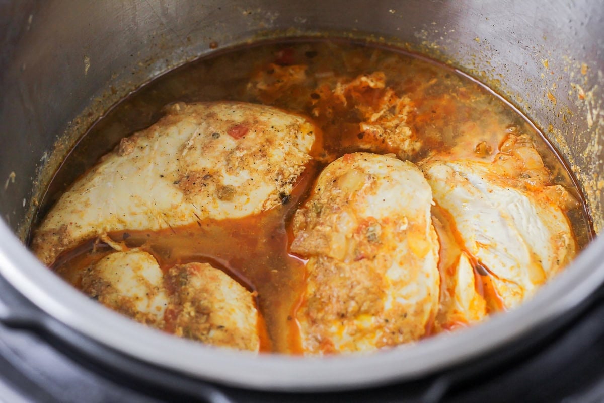 Cooked chicken and seasonings in an instant pot.