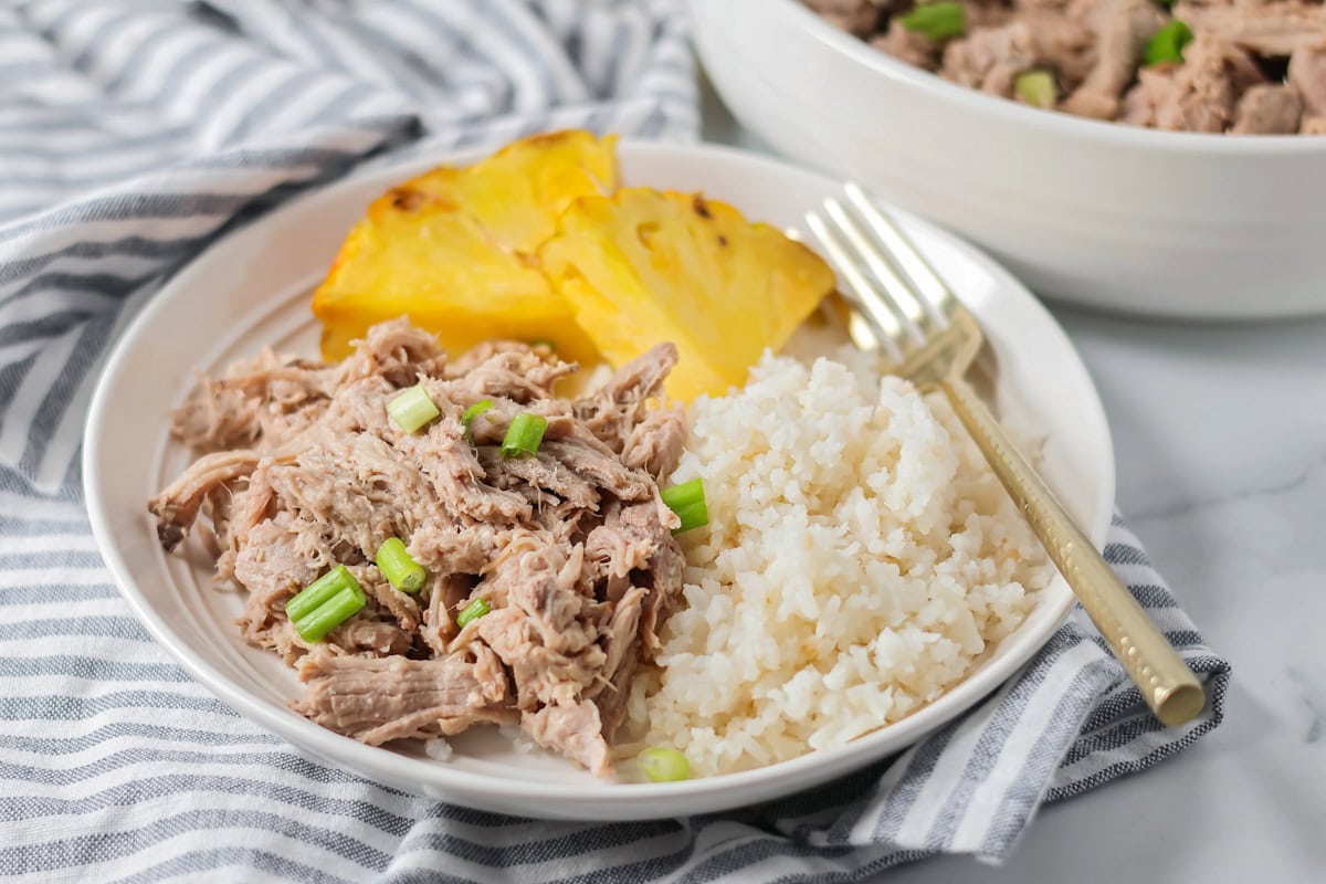 Kalua pork recipe served with rice and pineapple.