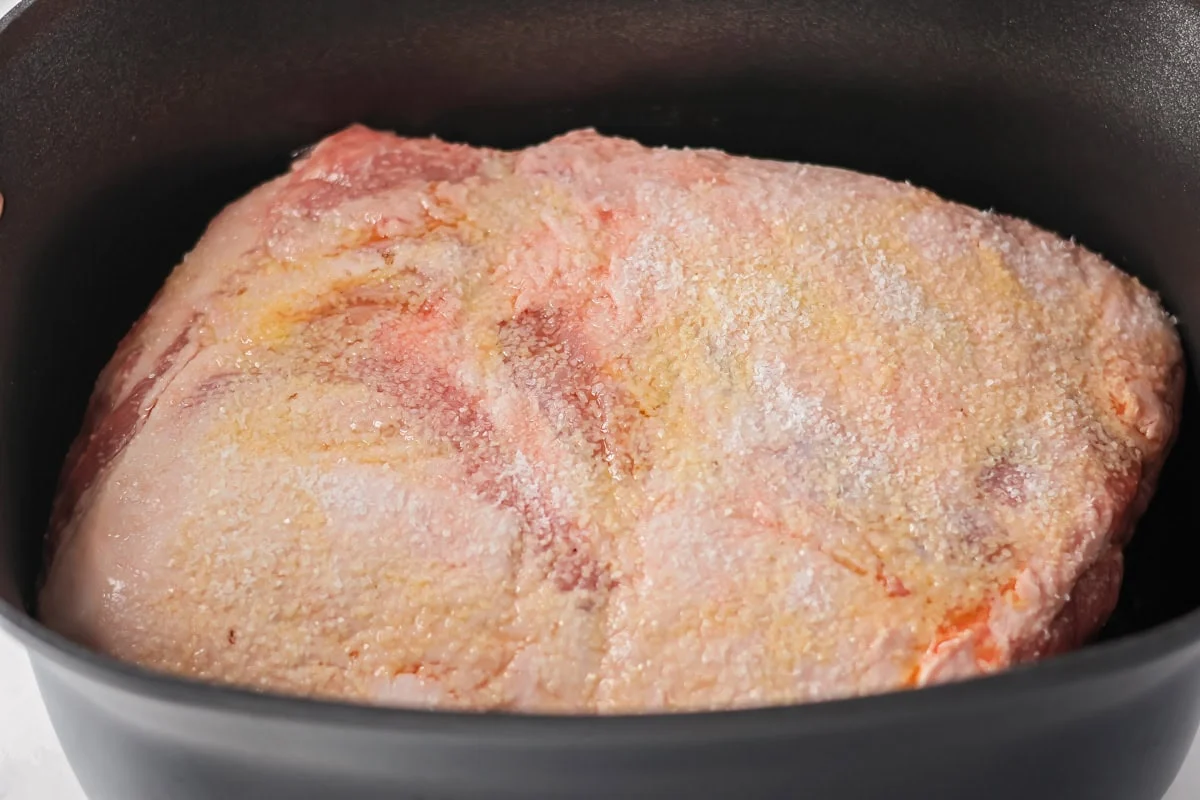 Pork roast in a slow cooker covered with seasonings.