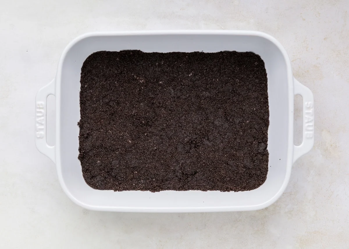 Oreo crust pressed in the bottom of a baking dish.