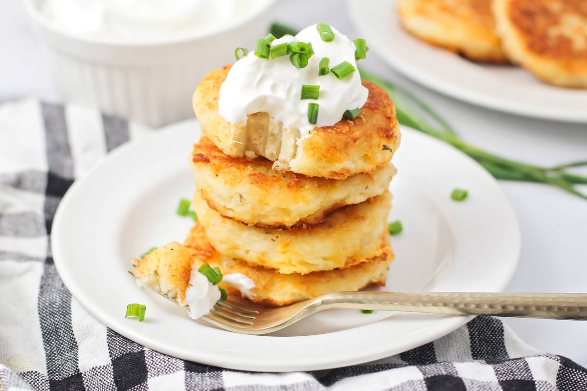 A stack of potato pancakes topped with sour cream and chives.