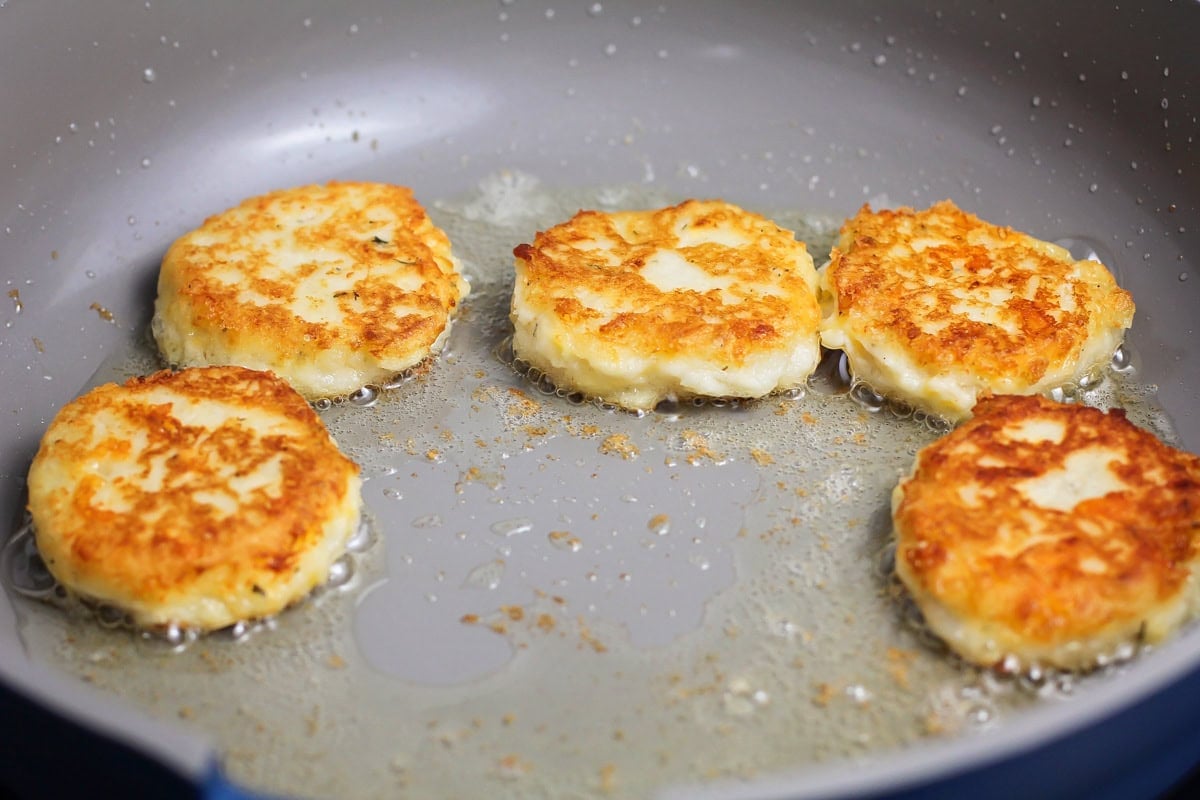Golden brown pancake patties cooking in a skillet of oil.
