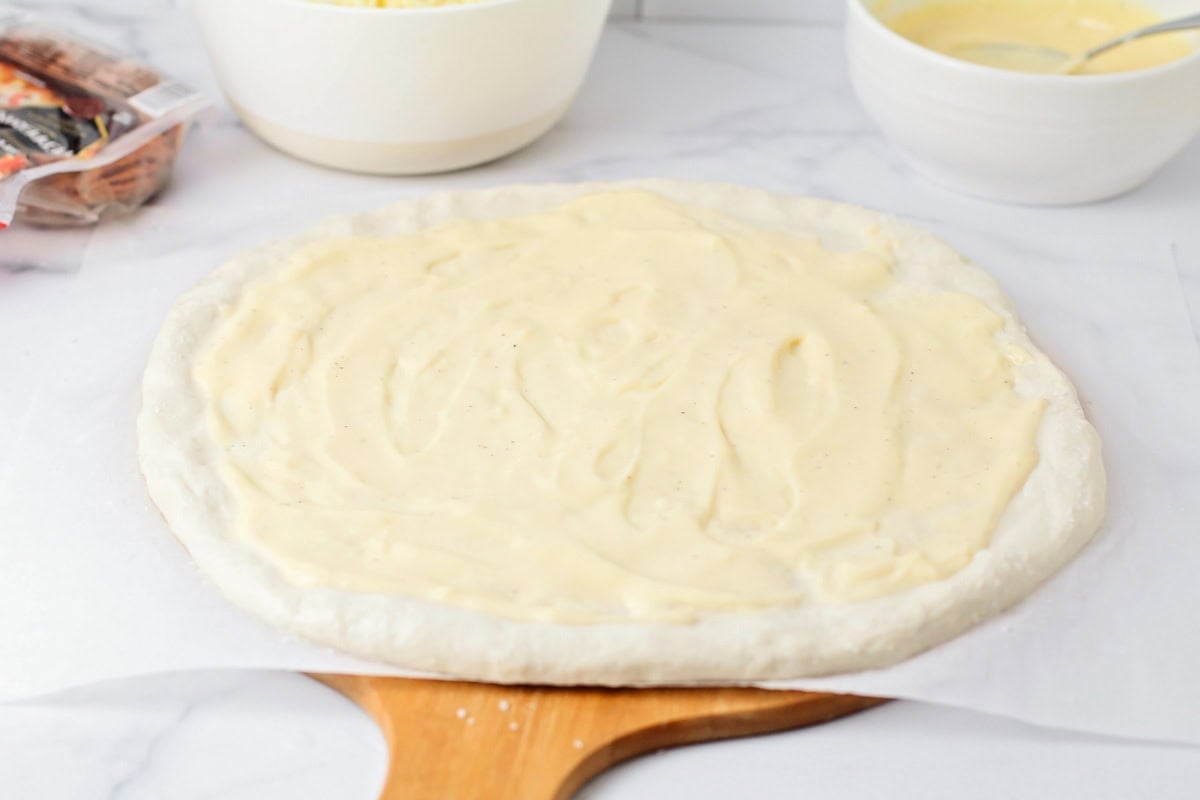 Cheese sauce spread on a pretzel pizza crust.