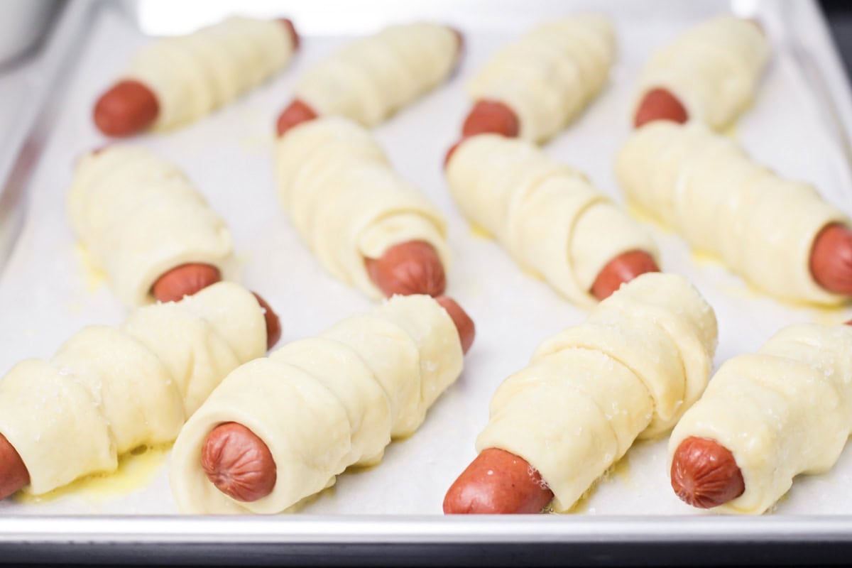 Dough wrapped hot dogs on a lined baking sheet.