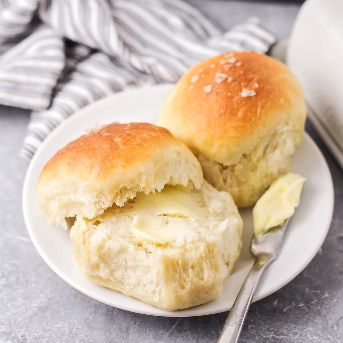 Two quick dinner rolls served on a plate with butter.