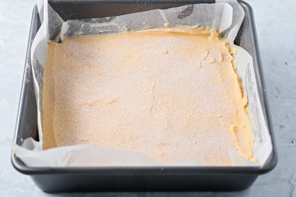 Cinnamon and sugar sprinkled over the batter in a lined baking pan.